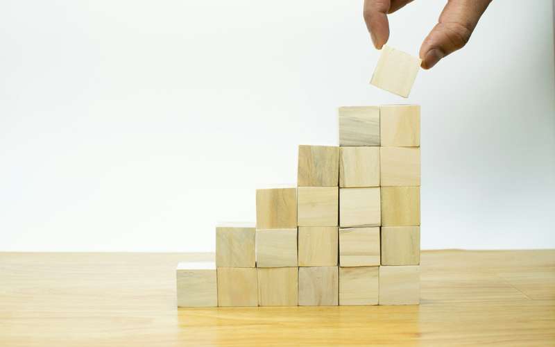 A person placing a piece of wood into a pyramid